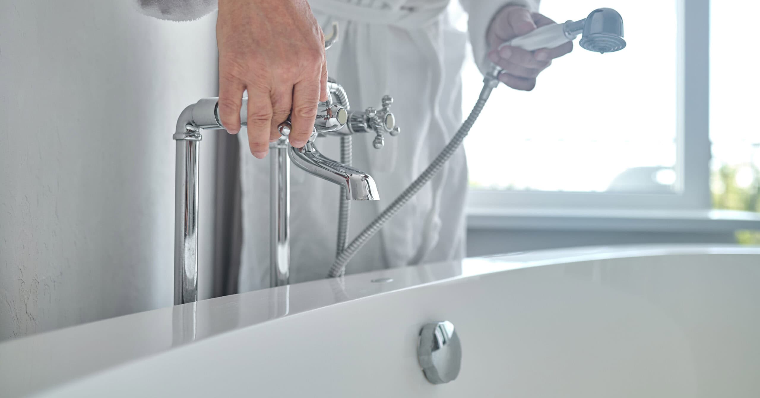 Man in a white terry bathrobe filling the bathtub with water Man in a white terry bathrobe filling the bathtub with water - bathtub cleaning