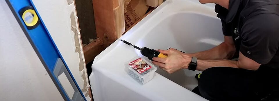Nail or screw the tub flange to every wall stud it touches