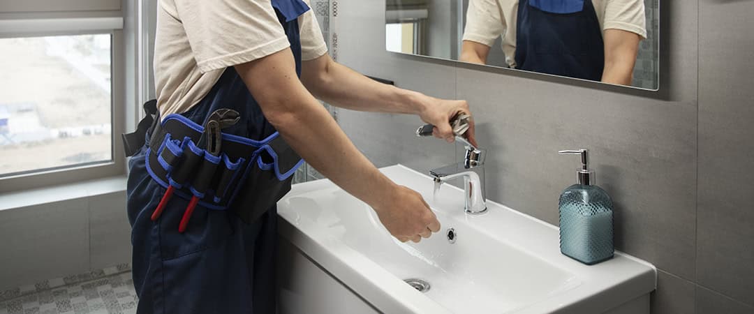 A plumber is installing basin tap
