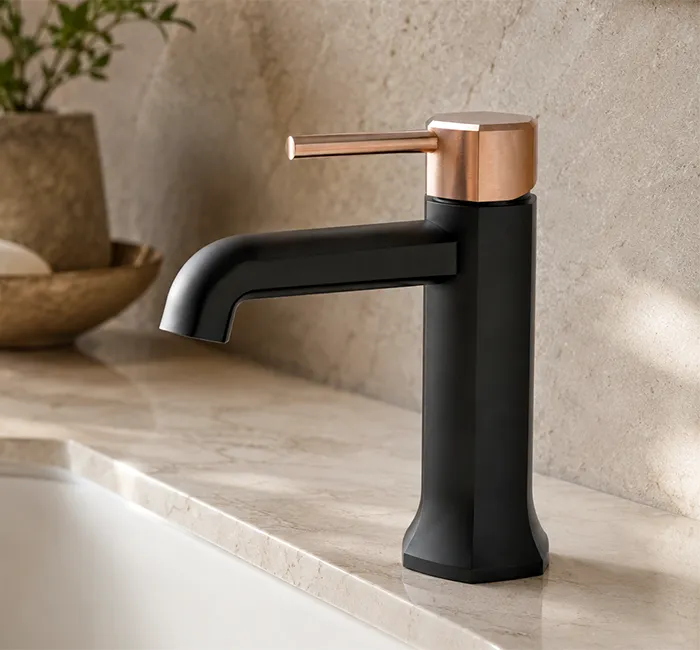 Matte black and rose gold basin faucet installed on a natural stone vanity in a modern luxury bathroom.